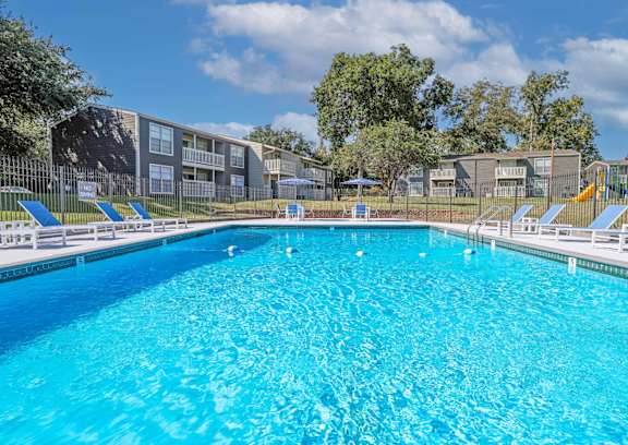 A playground with a yellow slide and a blue and green play structure at Maplewood apartments in Shreveport, LA.