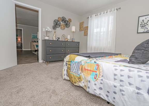 A cypress bedroom with a bed, dresser, and mirror at The Marq in Shreveport, LA