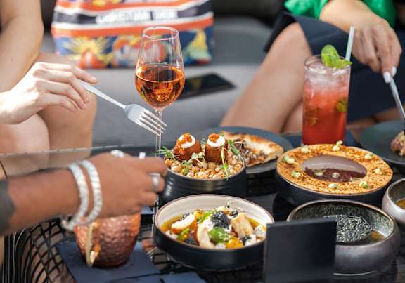 A person is eating a meal with a glass of wine.