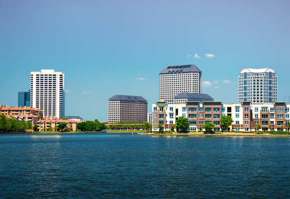 A cityscape with buildings and a body of water in the foreground.