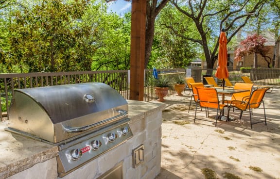 a backyard with a barbecue grill and a table and chairs
