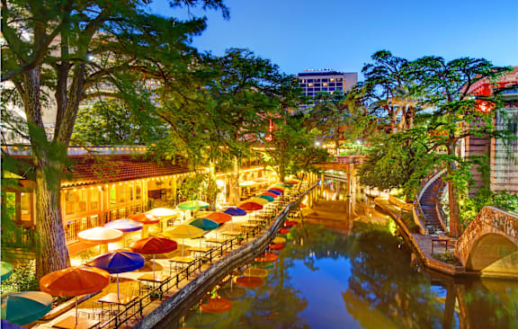 A beautiful riverside scene with a bridge and umbrellas.
