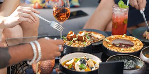 A person is eating a meal with a glass of wine.