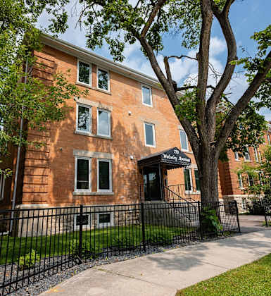 a brick building with a sidewalk and a wrought iron fence