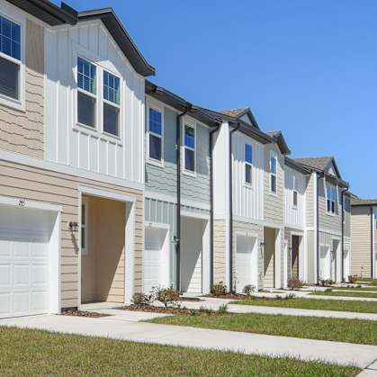 a row of townhomes with tan siding and white doors