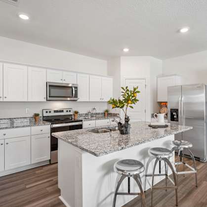an open kitchen with white cabinets and a marble counter top