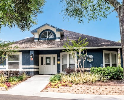 Leasing office exterior with lush landscaping at Reflections Apartments in Gainesville, FL