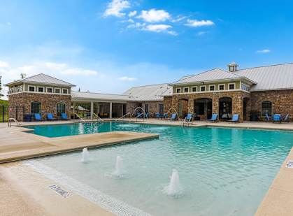 A large outdoor swimming pool with a fountain in the middle and a building in the background.