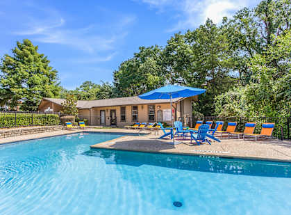 a pool with blue chairs and a house with a pool