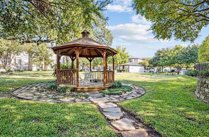 a gazebo in the middle of a yard with a stone pathway