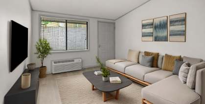 A living room with a grey couch, a black coffee table, and a flat screen TV mounted on the wall.