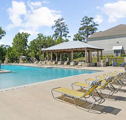 View of the pool with the shaded seating area and grill station at Capital Grand Apartments in Tallahassee, FL