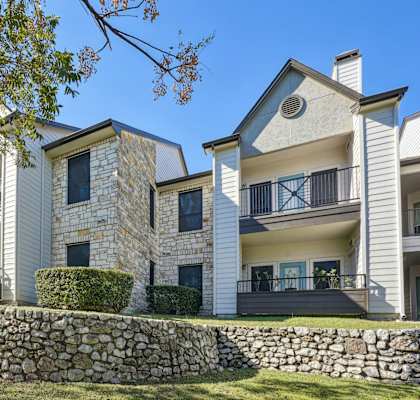 Our apartment buildings with balconies and a stone wall at On the Green apartments in Austin, TX