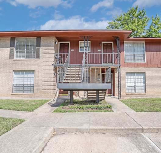 A two-story apartment building with a red roof and a stairway to the second floor at Orleans Square in Shreveport, LA