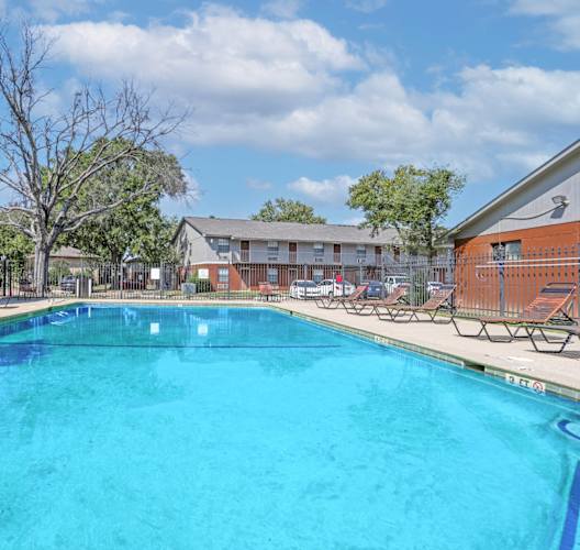 A large swimming pool with lounge chairs and apartment buildings in the background at Orleans Square in Shreveport, LA