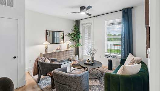 A living room with a grey couch, a green couch, a coffee table, and a ceiling fan.