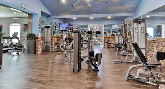 A gym with a variety of equipment including treadmills, weights, and exercise machines.