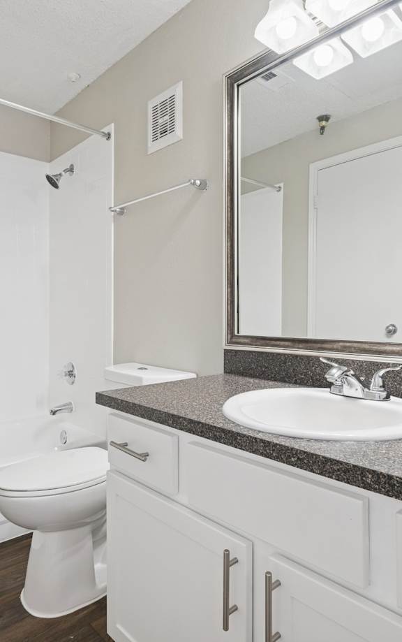 A bathroom with a toilet, sink, and mirror.