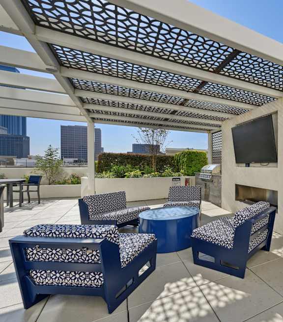 a rooftop deck with a bar and skyline in the background at Dominion Post Oak in Houston, TX