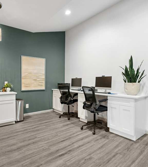 A room with four chairs and a desk with a computer.