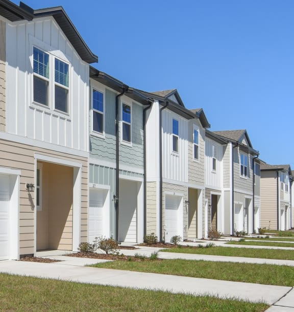 a row of townhomes with tan siding and white doors