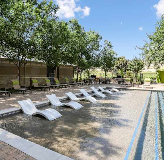 Our pool with in-pool lounge chairs at GreenVue apartments in Richardson, TX