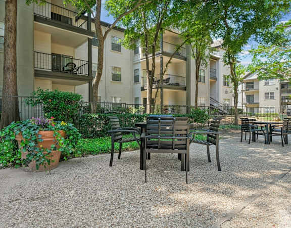 A patio with a table and chairs surrounded by a fence and trees.