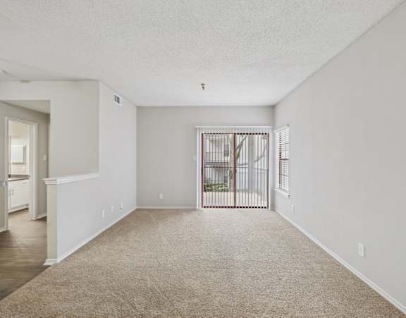 B1 living room with plush carpet and sliding door leading to private balcony at Jefferson Place apartments in Irving, TX