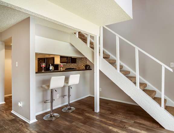 the model living room with white walls, white stools  and a staircase at Windridge in Dallas, TX