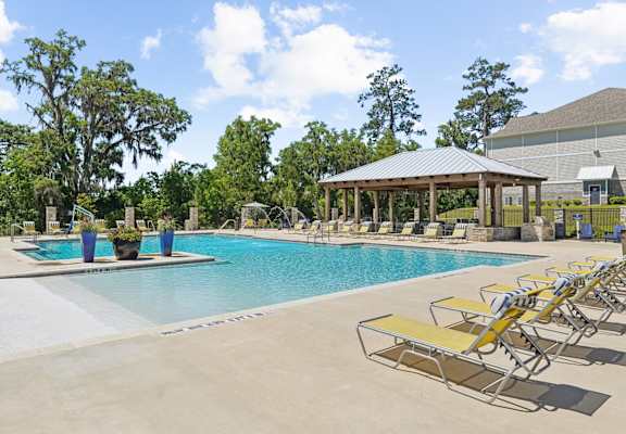 View of the pool with the shaded seating area and grill station at Capital Grand Apartments in Tallahassee, FL