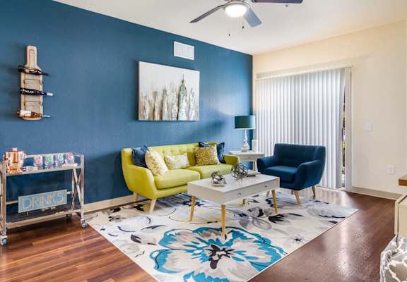 Model apartment living room with a navy blue accent wall, couch and blue chair at Oakleaf Plantation in Jacksonville, FL