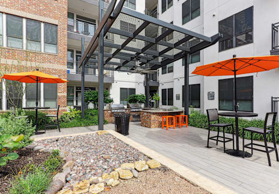 A patio with a table and chairs under an orange umbrella.