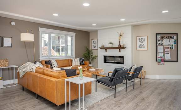A living room with a brown couch, a white coffee table, and a fireplace.