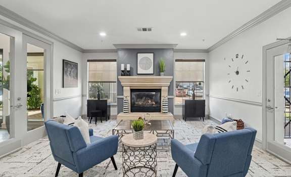 A leasing office with a fireplace and chairs at Encore at Buckingham Apartments in Richardson, TX