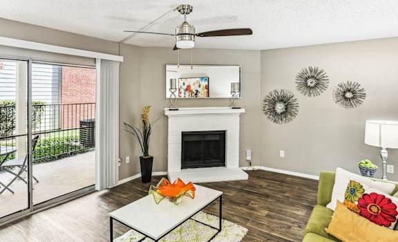 Model living room with a fireplace and a sliding glass door to patio at Hunters Chase in Austin, TX