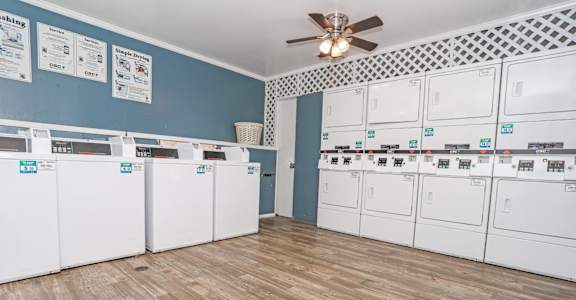 Onsite laundry room with blue walls washer and dryers at Maplewood apartments in Shreveport, LA.