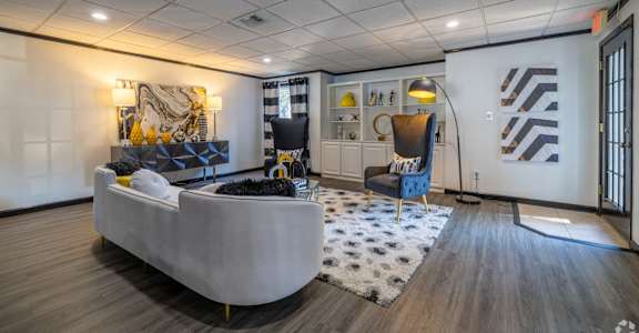 Cozy lounge in leasing office with a grey sofa and a patterned rug at Maplewood apartments in Shreveport, LA.