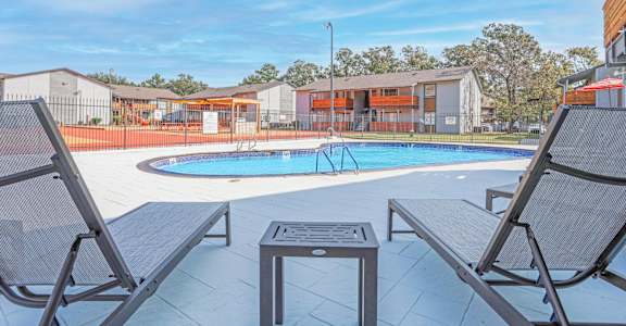 A pool surrounded by chairs and a table at The Marq apartments in Shreveport, LA