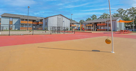 A playground with a red surface and a yellow ball on a pole at The Marq apartments in Shreveport, LA
