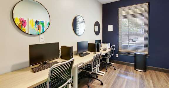 a room with three computers and a round mirror on the wall at Columbus Apartments in Columbus, Georgia, GA