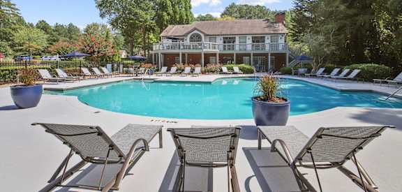 Our community pool surrounded by lounge chairs and the leasing office at Wellington Ridge Apartments in Lawrenceville, GA
