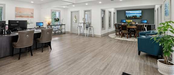 A modern leasing office with a wood floor and desks and chairs at Gwinnett Square Apartments in Duluth, GA