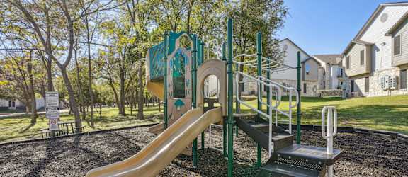 Our community playground with a slide, stairs and a climbing frame at On the Green apartments in Austin, TX