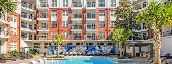 A large swimming pool in front of a multi-story apartment building.