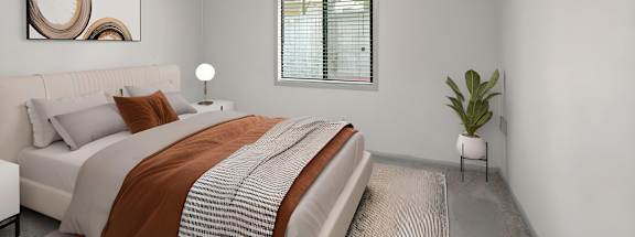 A bedroom with a bed, a ceiling fan, and a plant.