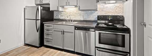 A modern kitchen with stainless steel appliances and wooden flooring.
