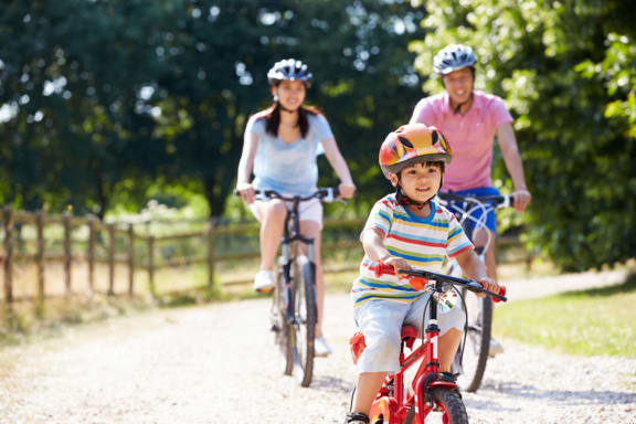a young boy riding a bike with his parents behind him
