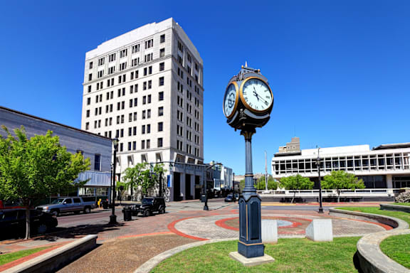 A large white building with a clock on a pole in front of it.
