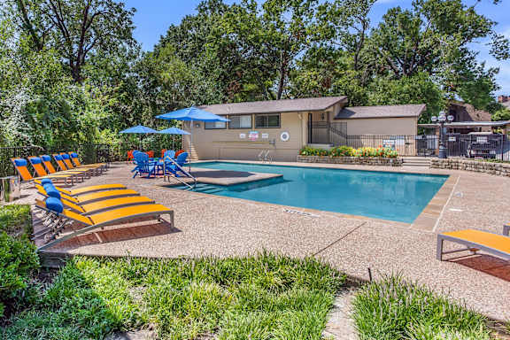 A pool surrounded by trees and a house.
