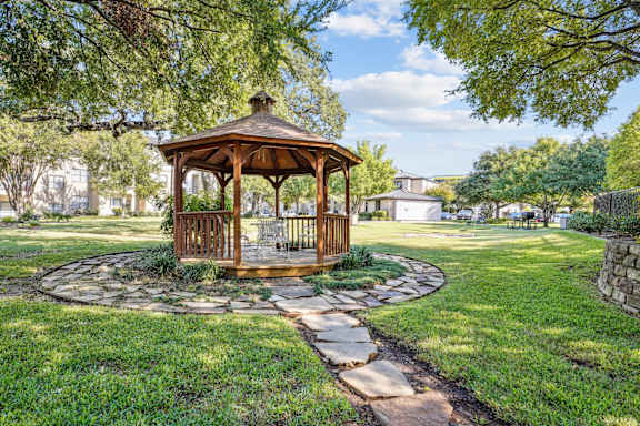 a gazebo in the middle of a yard with a stone pathway